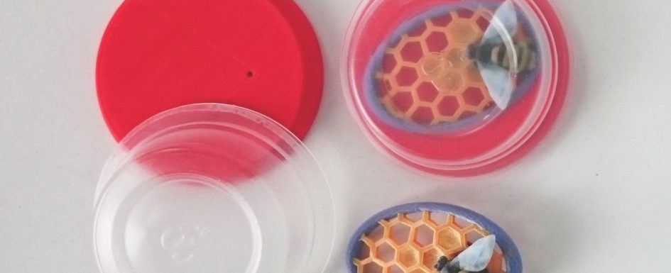 Plastics are precious: Ann Marie Shillito's 'Bee Brooch'. Ann Marie designed the red 3D printed lid to fit a clear plastic tub from Simply Cook which she has repurposed here as a packaging and display box.